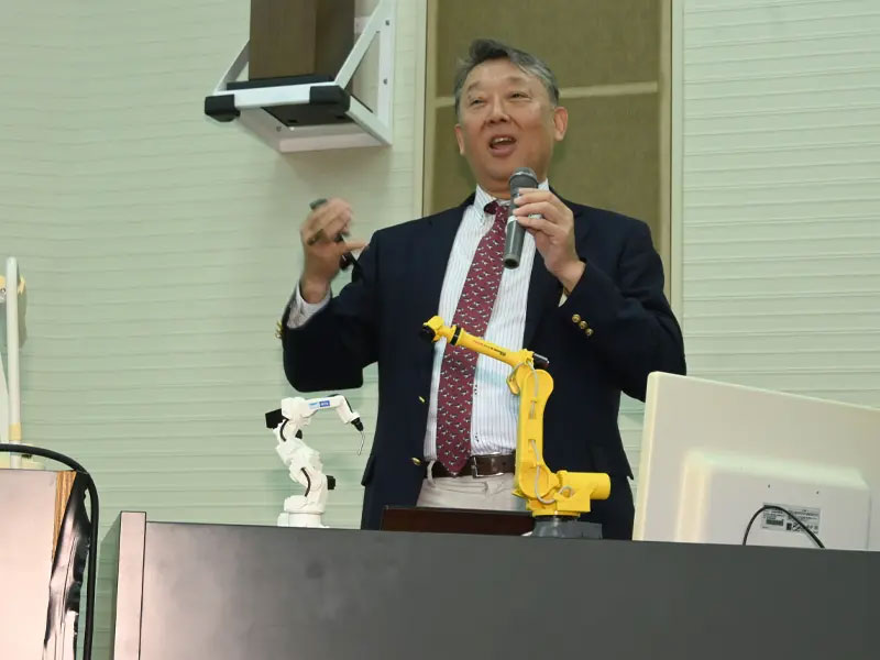 ロボットの模型を見せながら講演する髙丸社長